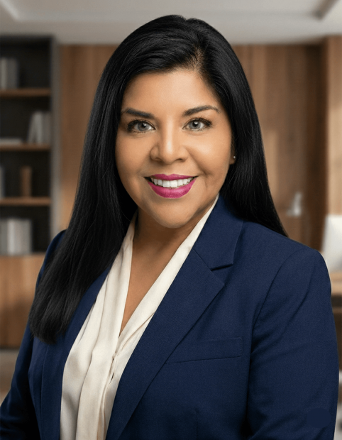 Professional headshot of Gabriella San Miguel, President of Cocha Technology, wearing a navy blue blazer and white blouse in a modern office setting.